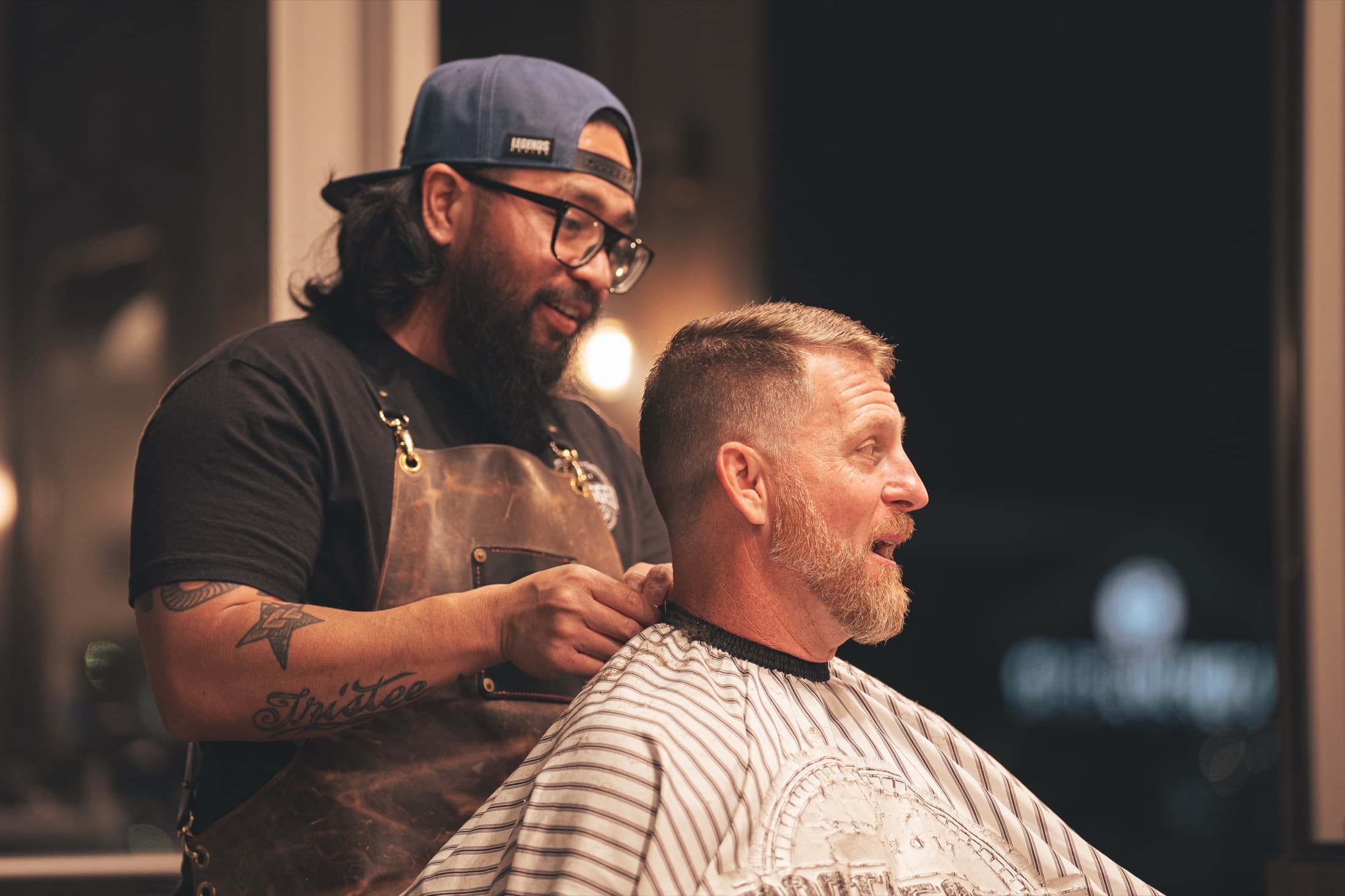 Barber laughing with a bearded client with a fresh fade