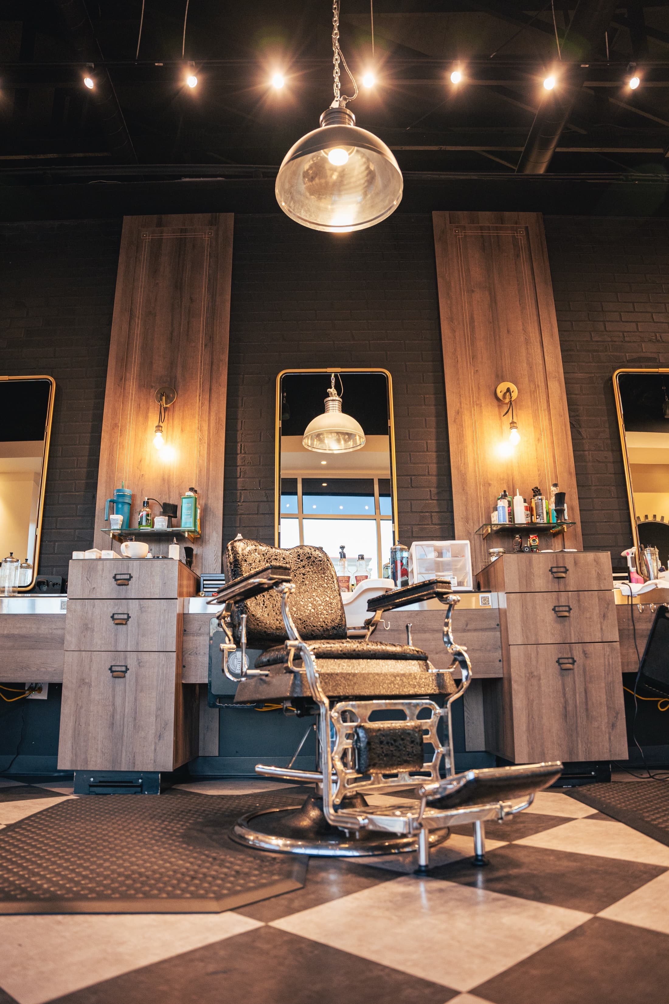Vintage barber chair between warm wood stations and gold-framed mirrors at Bootlegged Barber